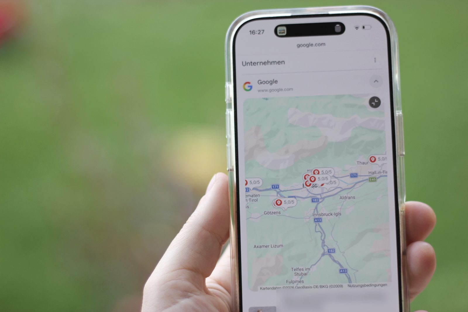 Hand hält ein Smartphone mit geöffneter Kartenansicht und Suchergebnissen
